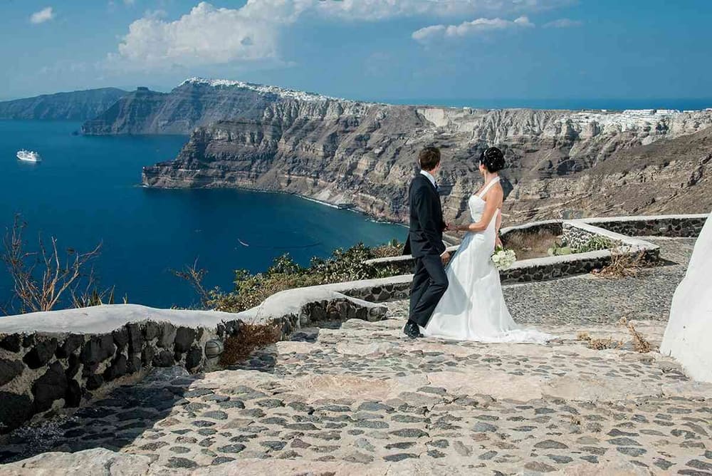 Couple walking along Santorini caldera path with sea view