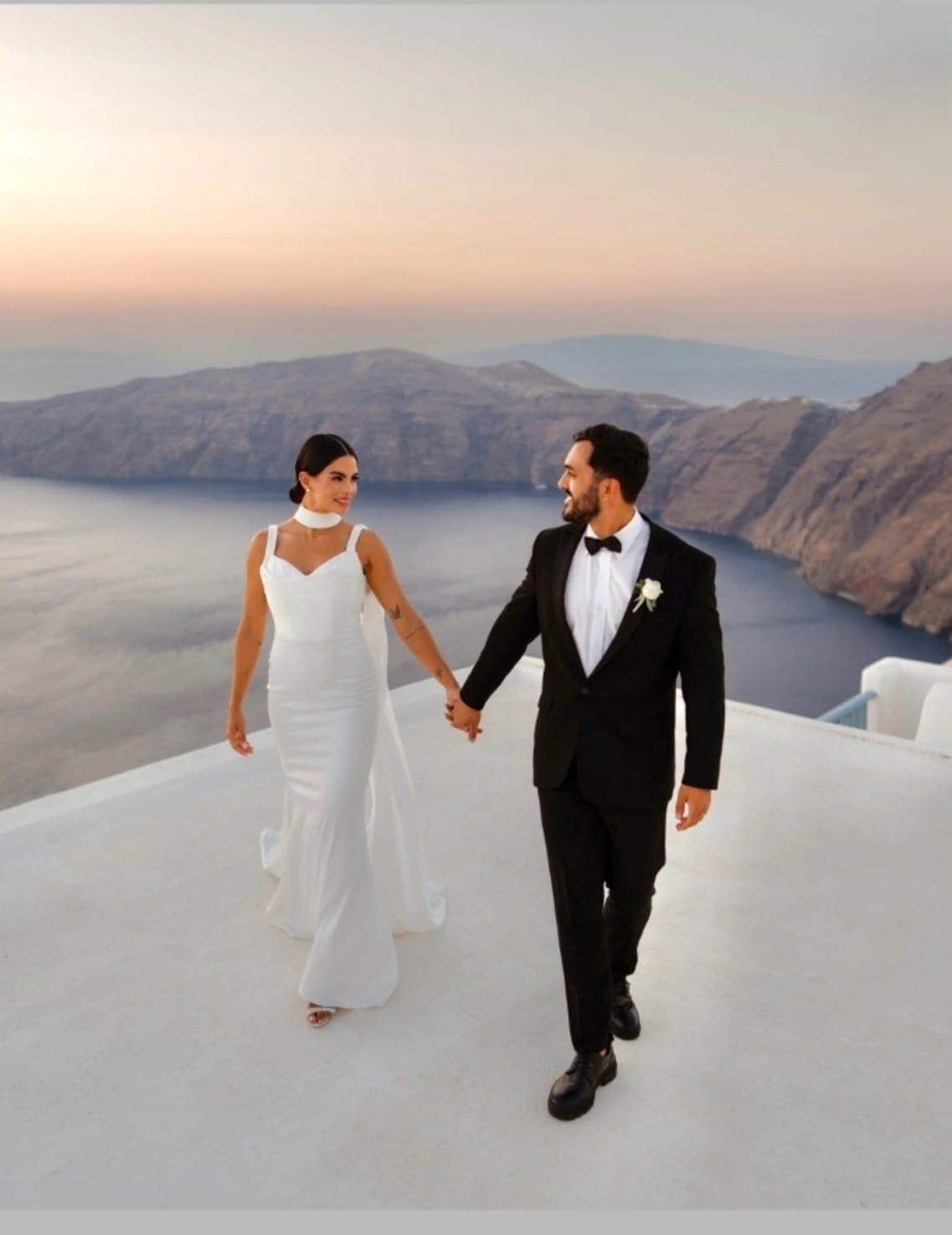 Couple walking at Santorini caldera during golden hour